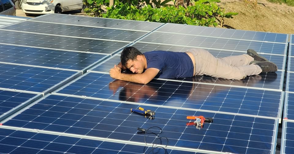 Técnico descansando sobre un arreglo de paneles solares terminado